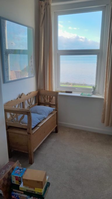 Pine bench in front of a window with sea view