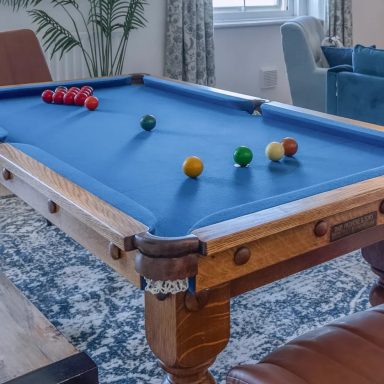 An antique pool table with a blue cloth and set of pool balls.