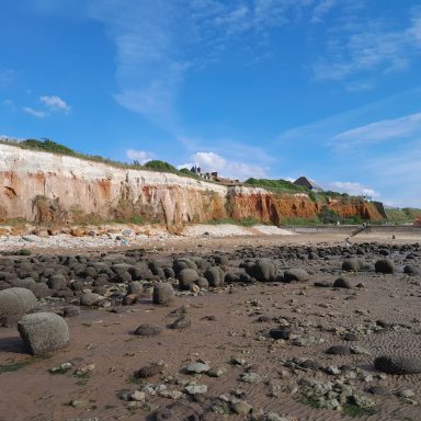 Beach and cliffs with a building on top. Blue sky.